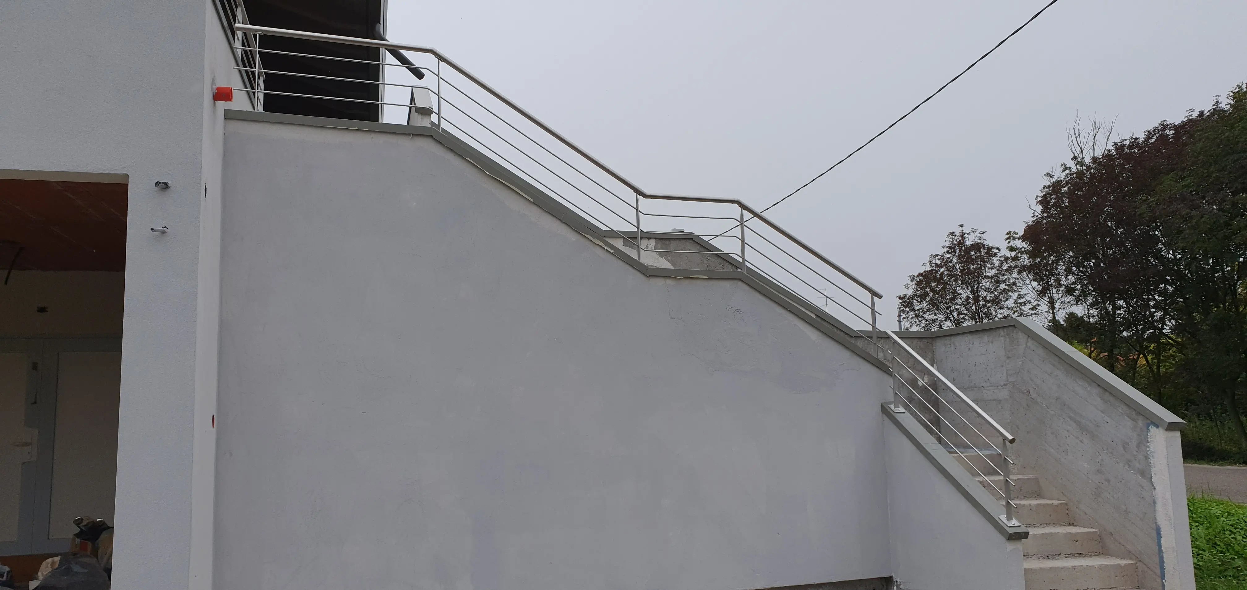 Parapetto sopra muretto esterno composto da lame e tondini inox