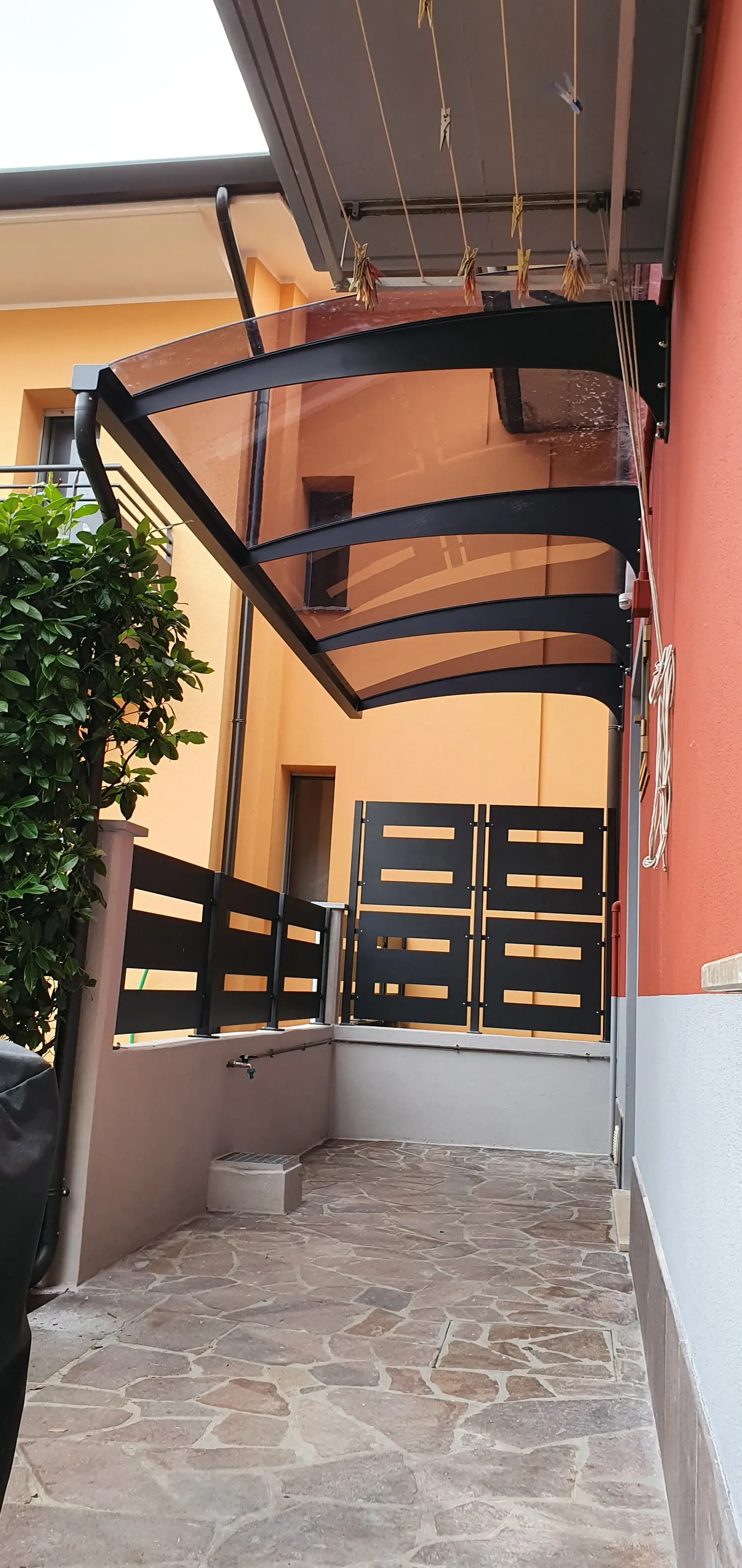 Tettoia con struttura in ferro e copertura in policarbonato fumè grigio